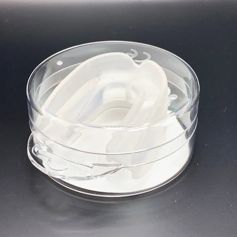 Clear plastic container with white silicone mouthguard on a black background