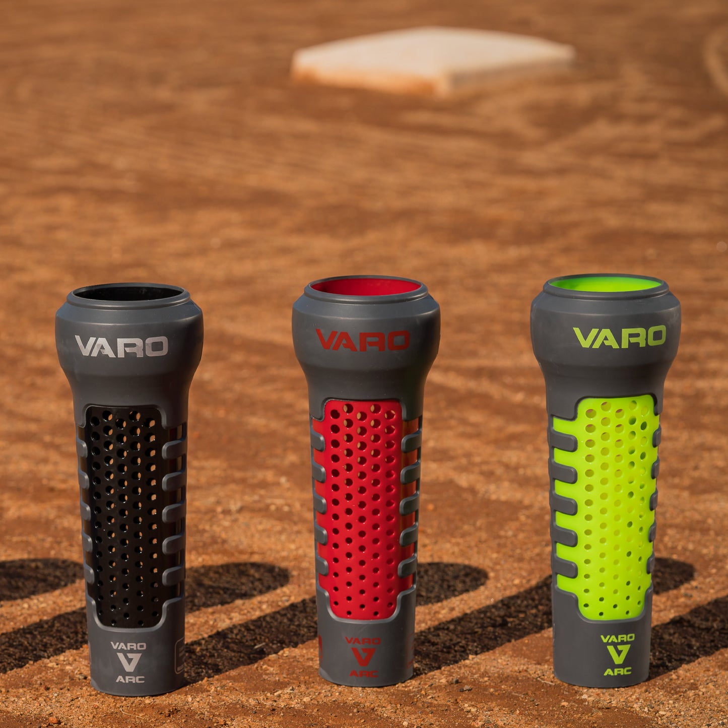 Three Varo ARC Bat Weight 12 Oz  in black, red, and hyper green on a baseball field background