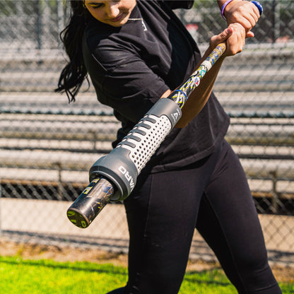 Person holding a baseball bat with Varo ARC Bat Weight 12 Oz on it, on a sports field with blurred background